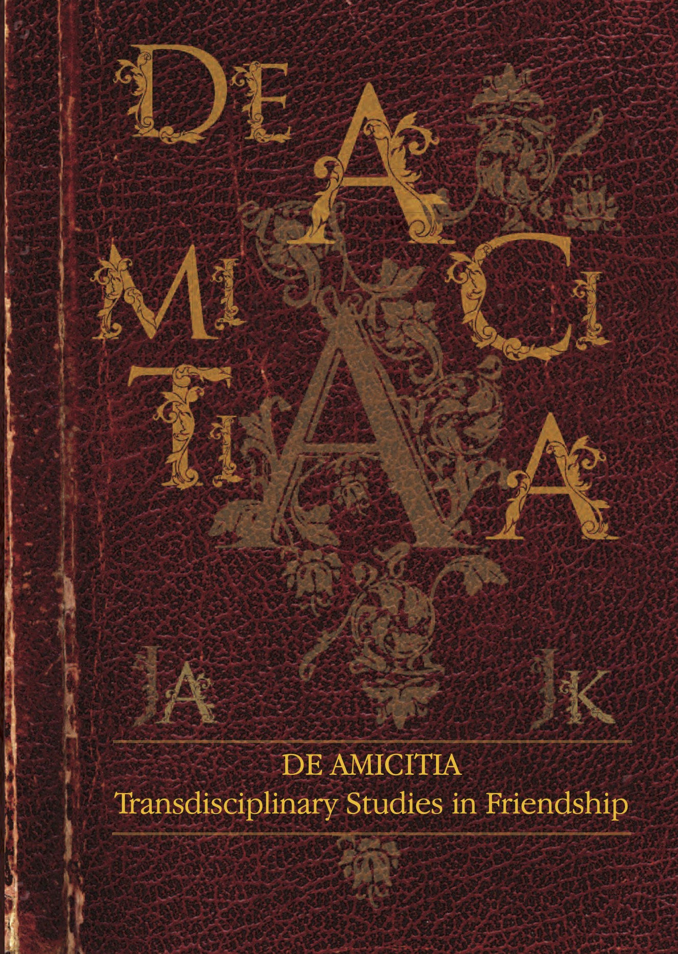 Okładka książki De amicitia. Transdisciplinary Studies in Friendship – stylizowana, bordowa oprawa przypominająca starą księgę, złocony tytuł „De Amicitia” oraz ornamenty nawiązujące do tradycji antycznej i humanistycznej